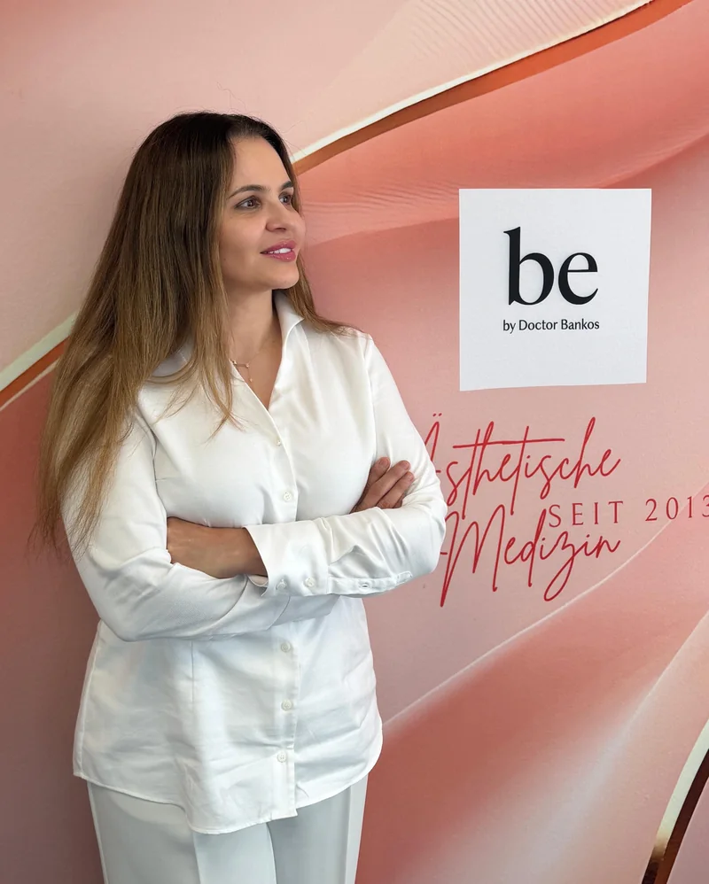 Doctor-medic Gabriela Bankos vor der Wand mit dem Logo be by Doctor Bankos