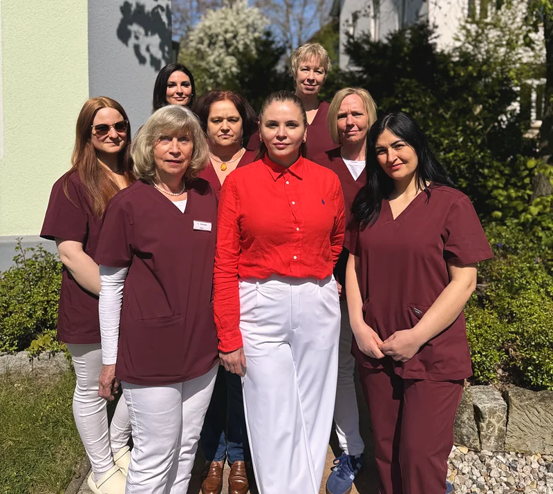 Das Team der Praxis draußen vor dem Haus in der Sonne